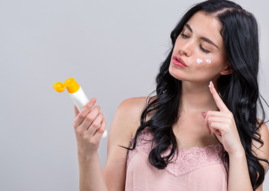 Mujer aplicando protector solar con maquillaje